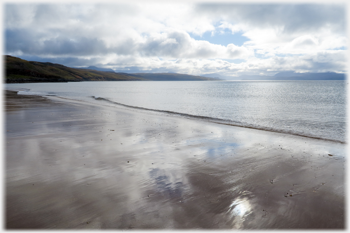 Wet sand reflecting the clouds and blue of the sky.