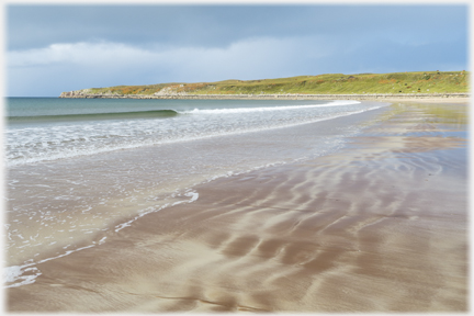 Looking along the beach with tide markings on the sand.