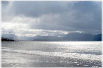 Dark clouds with light coming through to the sea.