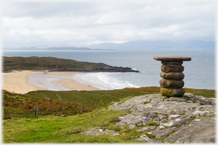Circular stone direction indicator overlooking bay with hills on the horizon.
