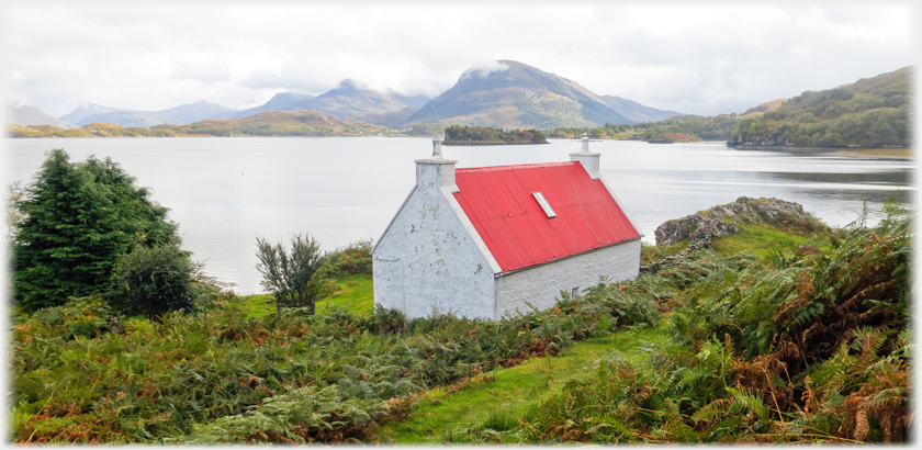Red roofed house with a little mist on hill beyond the loch.