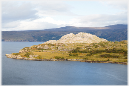 Peninsular in front of headland with hills beyond.