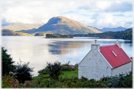 Red roofed house with hill lit by evening light.