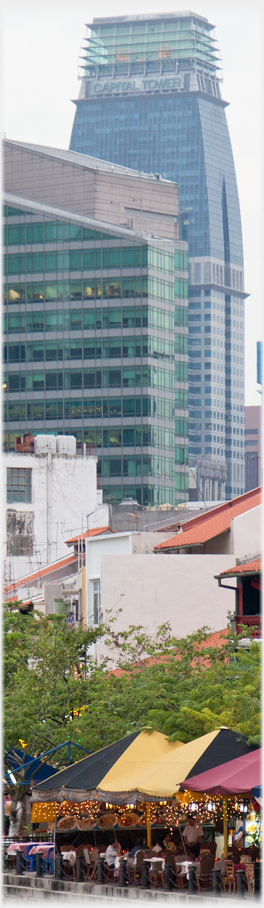 Capital Tower looming above a river cafe.