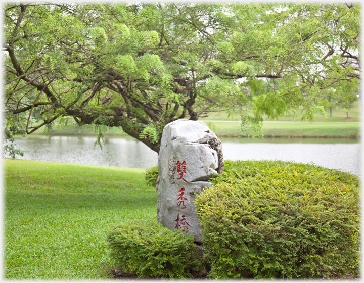 Rock with characters, tree and shrub.