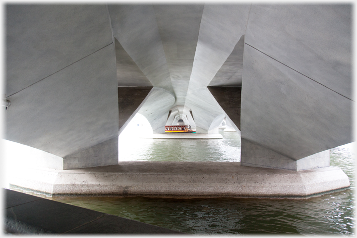 Looking through the piers of the Esplanade Bridge with boat passing.