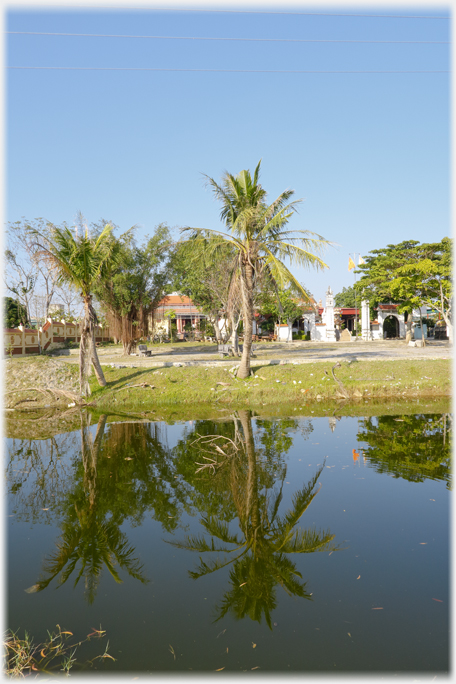 The Khanh Pagoda among the palm trees reflected in the river.