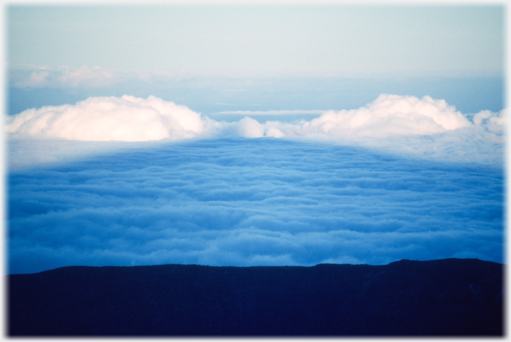 Triangular shadow of mountain cast on clouds.