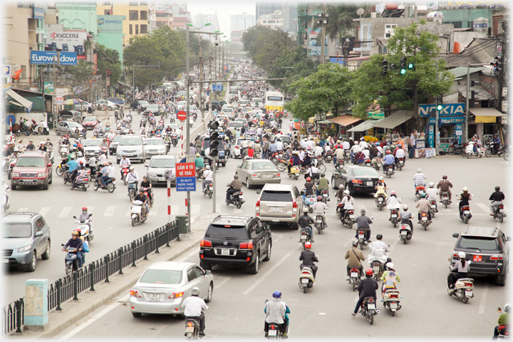 Wide street of cars and motorbikes.