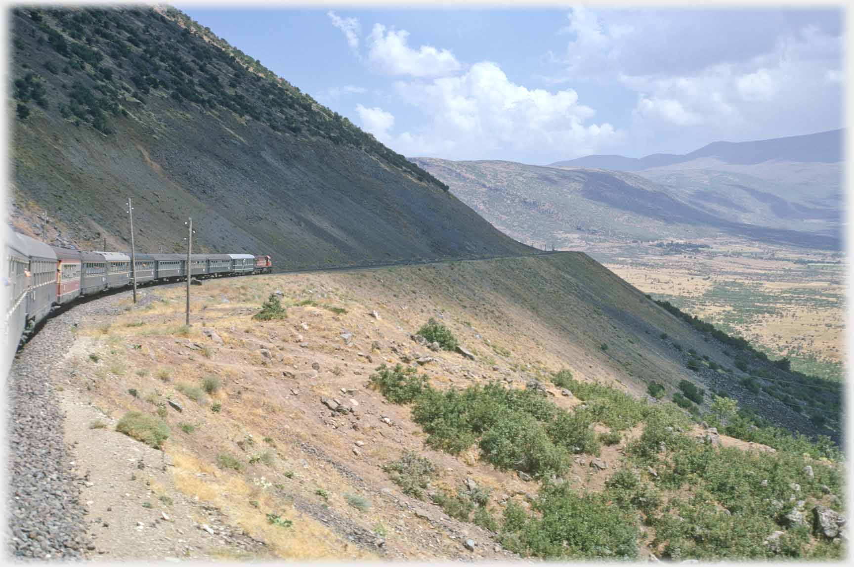 Train on railway curving around mountainside.