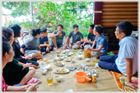 Family eating meal sitting on mats.