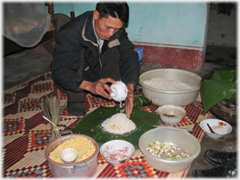 Hien sitting on a mat with ingredients all around him.