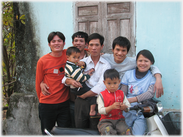 Four men, a woman and two children grouped around a motorbike.