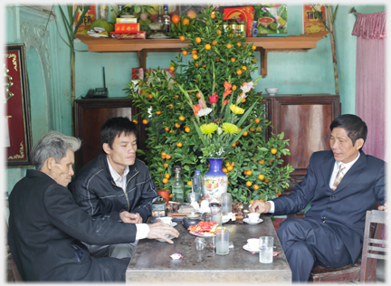 Three men sit in separate seats by table.