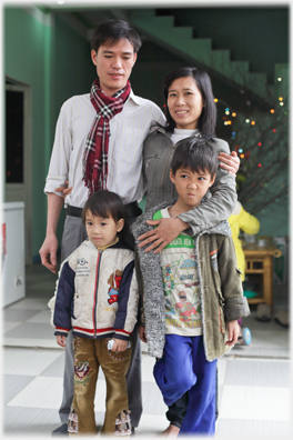 Loi, wife and two children on front door step.