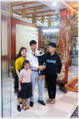 Han, Duyen and children in front of a tree in the reception room.