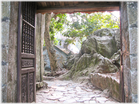 Looking on through the gateway to rocks and roofs.