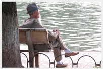 Man sitting quietly beside water.