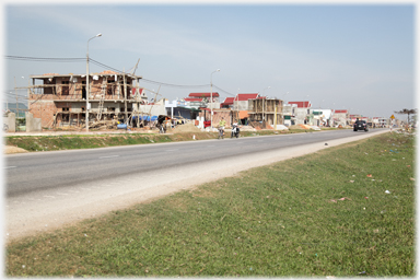 Road and embankment with large houses in various states of completion beyond.