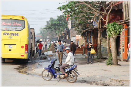 Man waiting on his motorbike wearing a craash helmet near a bus.