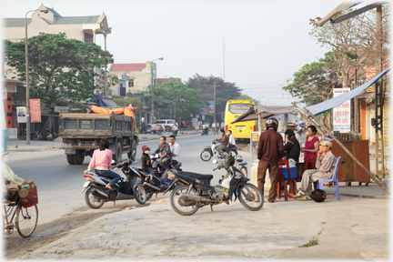 People standing, bikes parked, traffic passing.