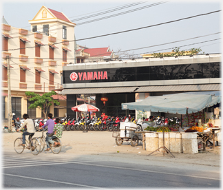 Yamaha showroom with stalls between it and the road and passing cyclists.