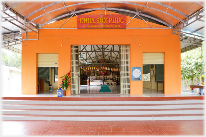 Front facade of the building with three doors and large name plaque over the door.