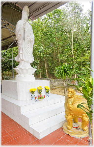 White Buddha statue with flower offerings.