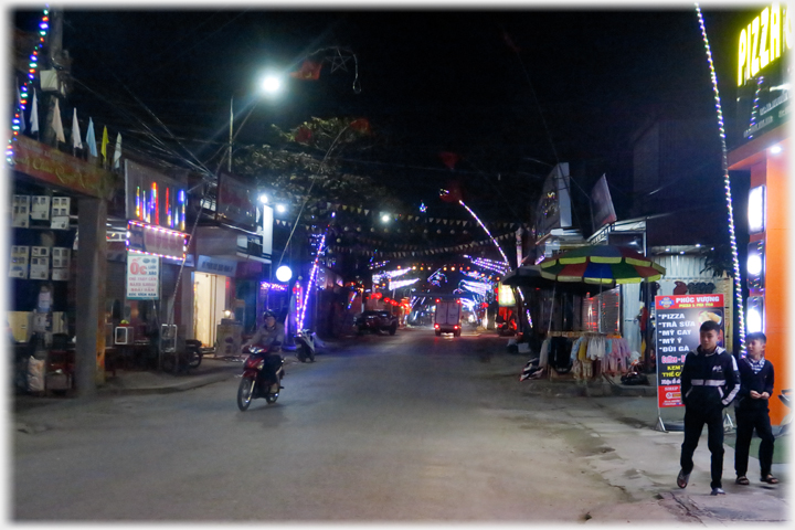 Two children standing by Pizza cafe and motorbike with no lights.