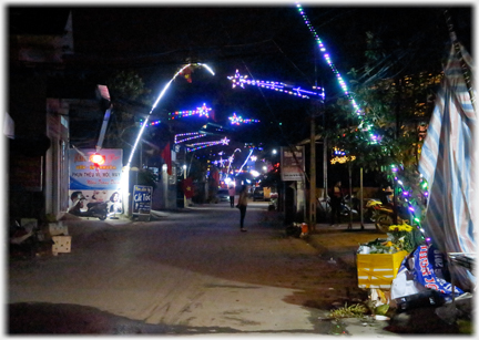 Lights as stars held on horizontal lit supports over street.