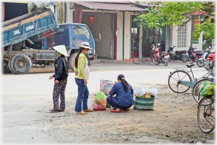 A woman with bags on a street corner, a customer looking on.