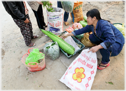 A woman with her goods in a line and the feet of three customers in front of her.