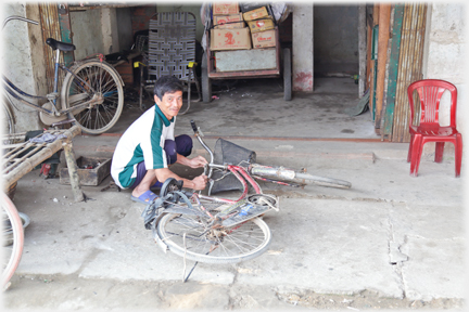Man squatting repairing bicycle.