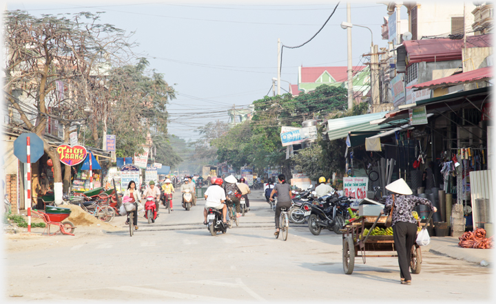 Cycles, motorbikes and hand cart on the main shopping street.