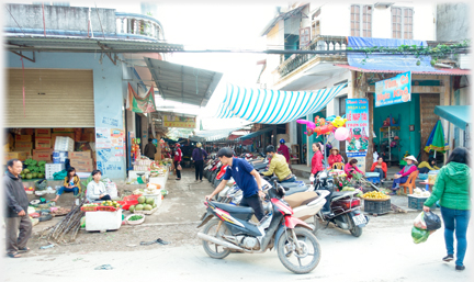 Side entrance to the market with man moving a motorcycle into a line.