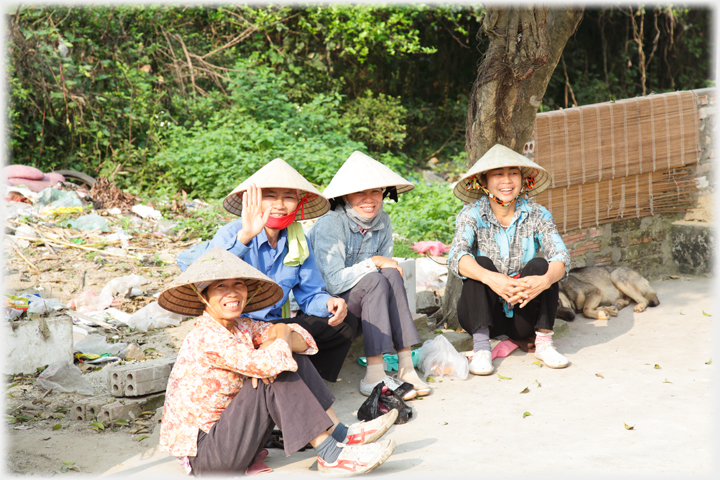 Four happy looking women sitting at the roadside.