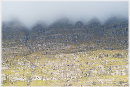 Cliff face with cloud filling top serrations.