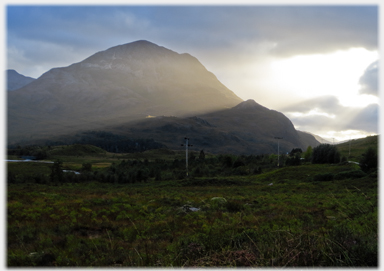 Shafts of light cutting dark outline of hill.