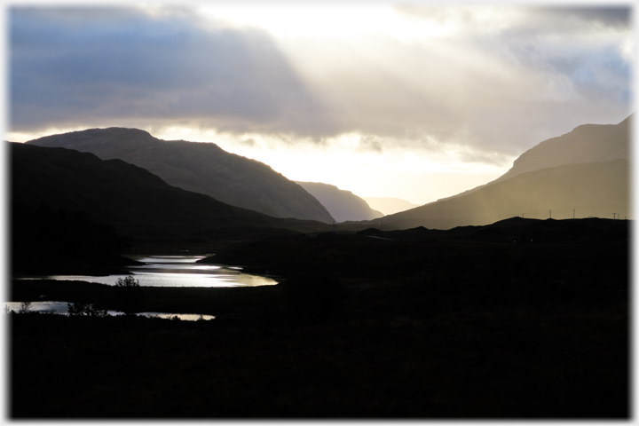 Silhouetted hills and evening light with foreground river.