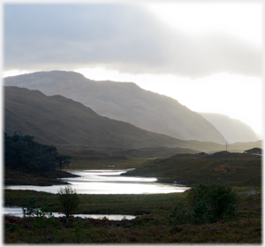 Hills outlined in evening with river running towards them.