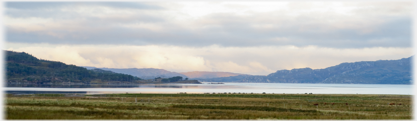 Panarama of the loch with low hills and pink light.