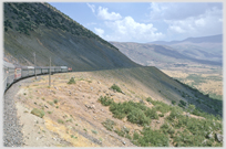 Train on track around mountain side.
