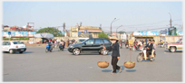 Woman carrying panniers crossing road intersection.