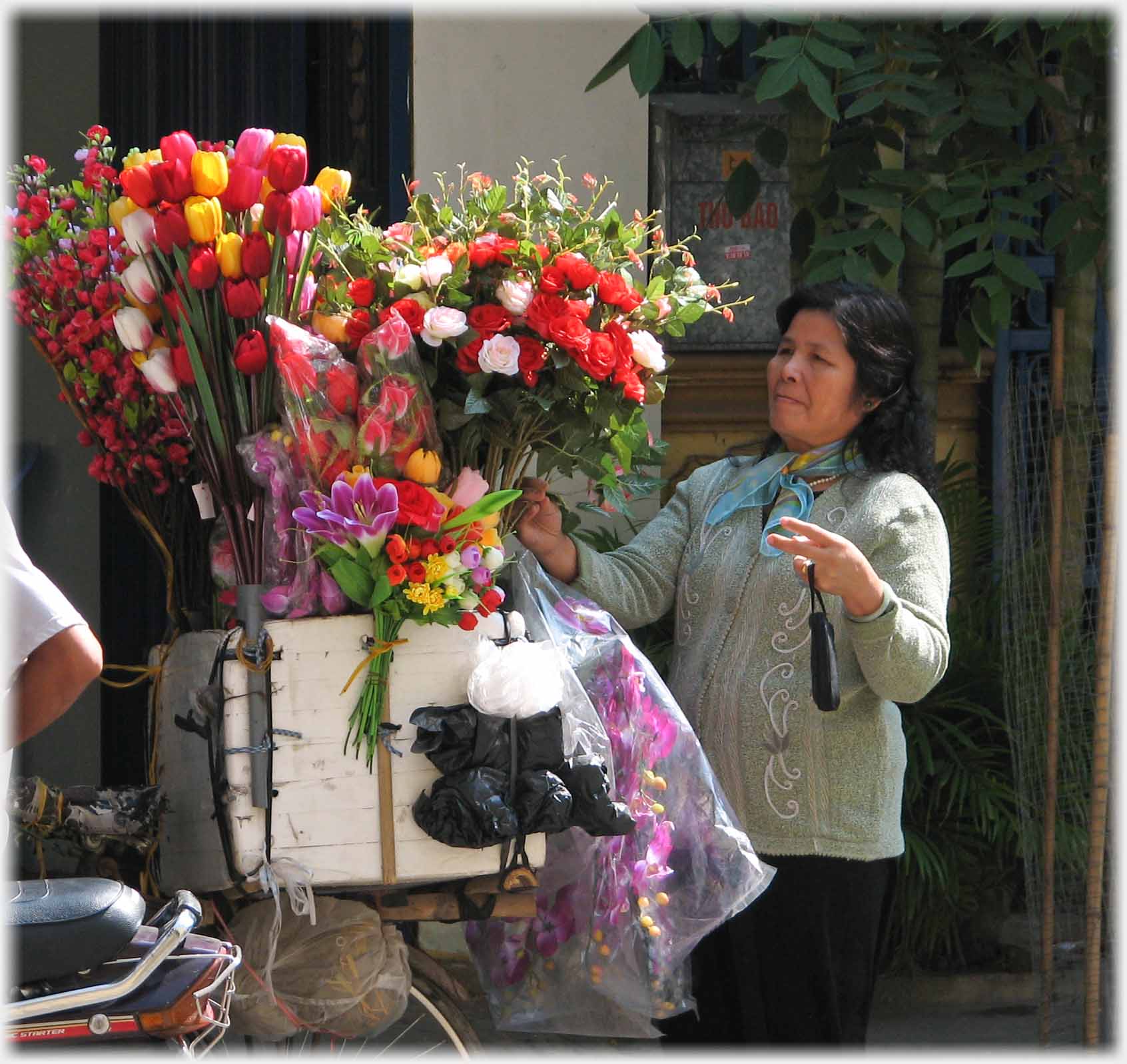 Woman beside bunches of flowers on a bicycle.