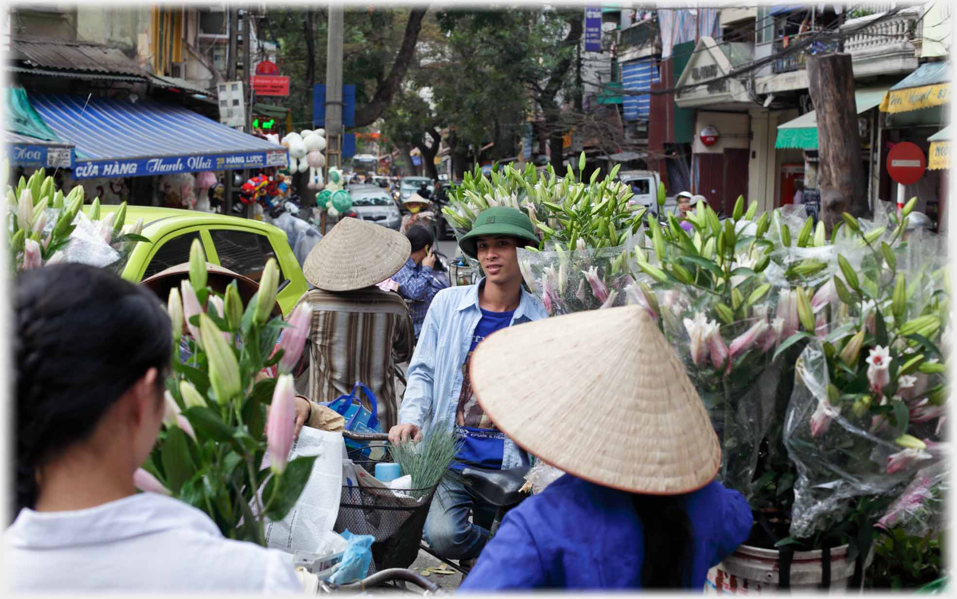 Many bikes with tall piles of lilies, a man and women amongst them.