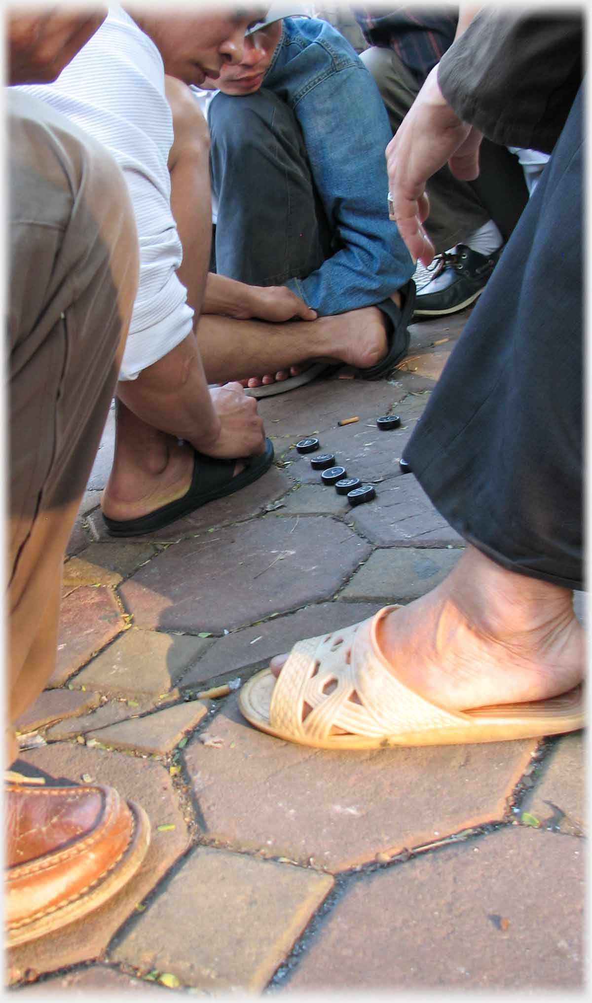 Chess pieces on paving stones between feet.