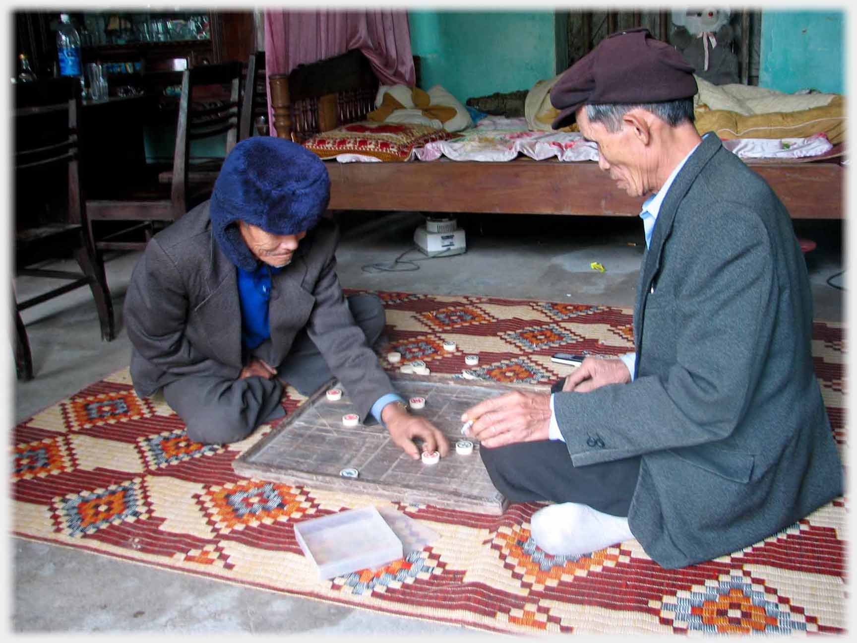 Two men playing, one setting piece on board.