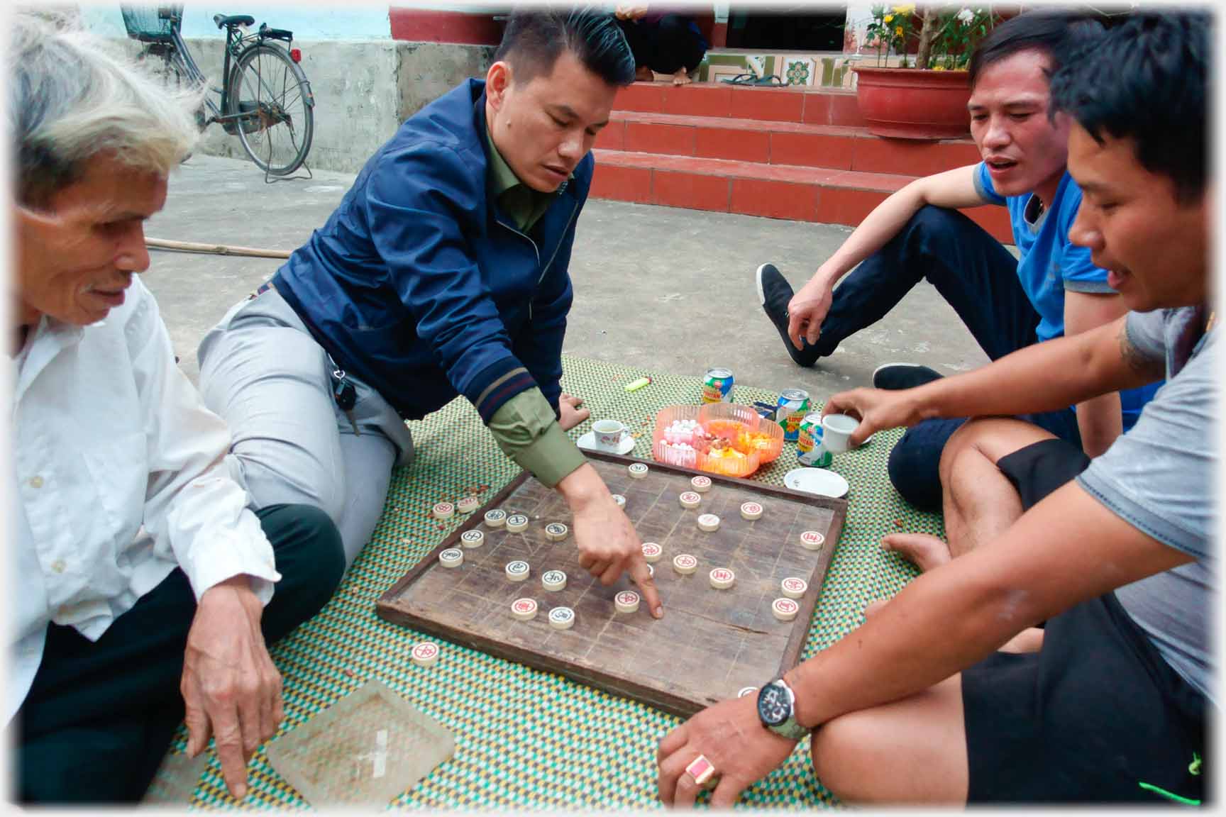 Four men on mat playing and watching a game.