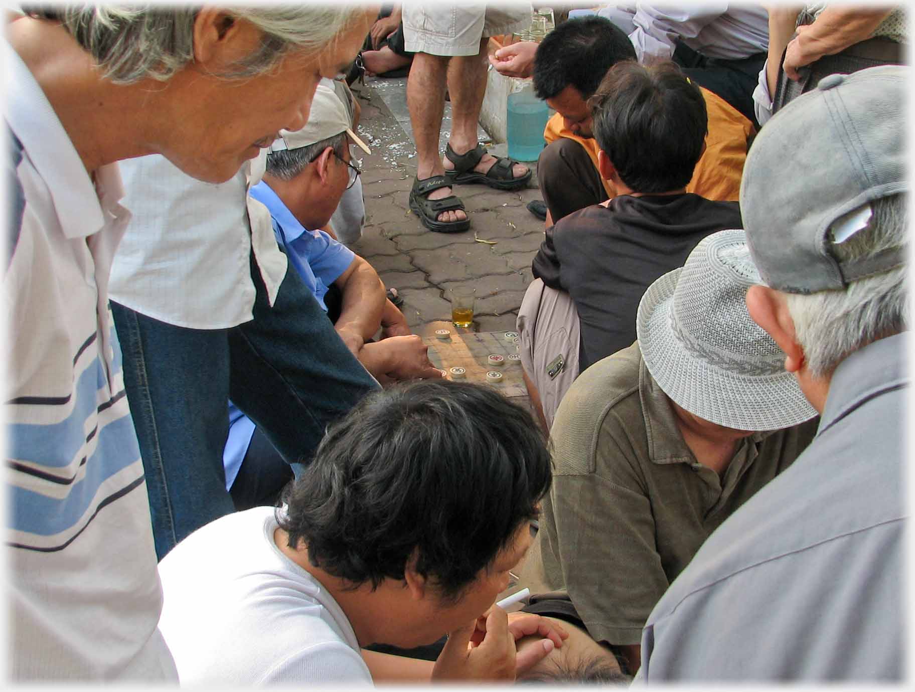 Huddle around chess game, glass of tea centre.