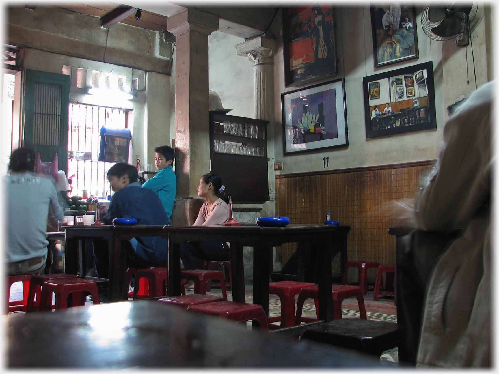 Three men and a woman leaning back from a conversation, wall covered in pictures.